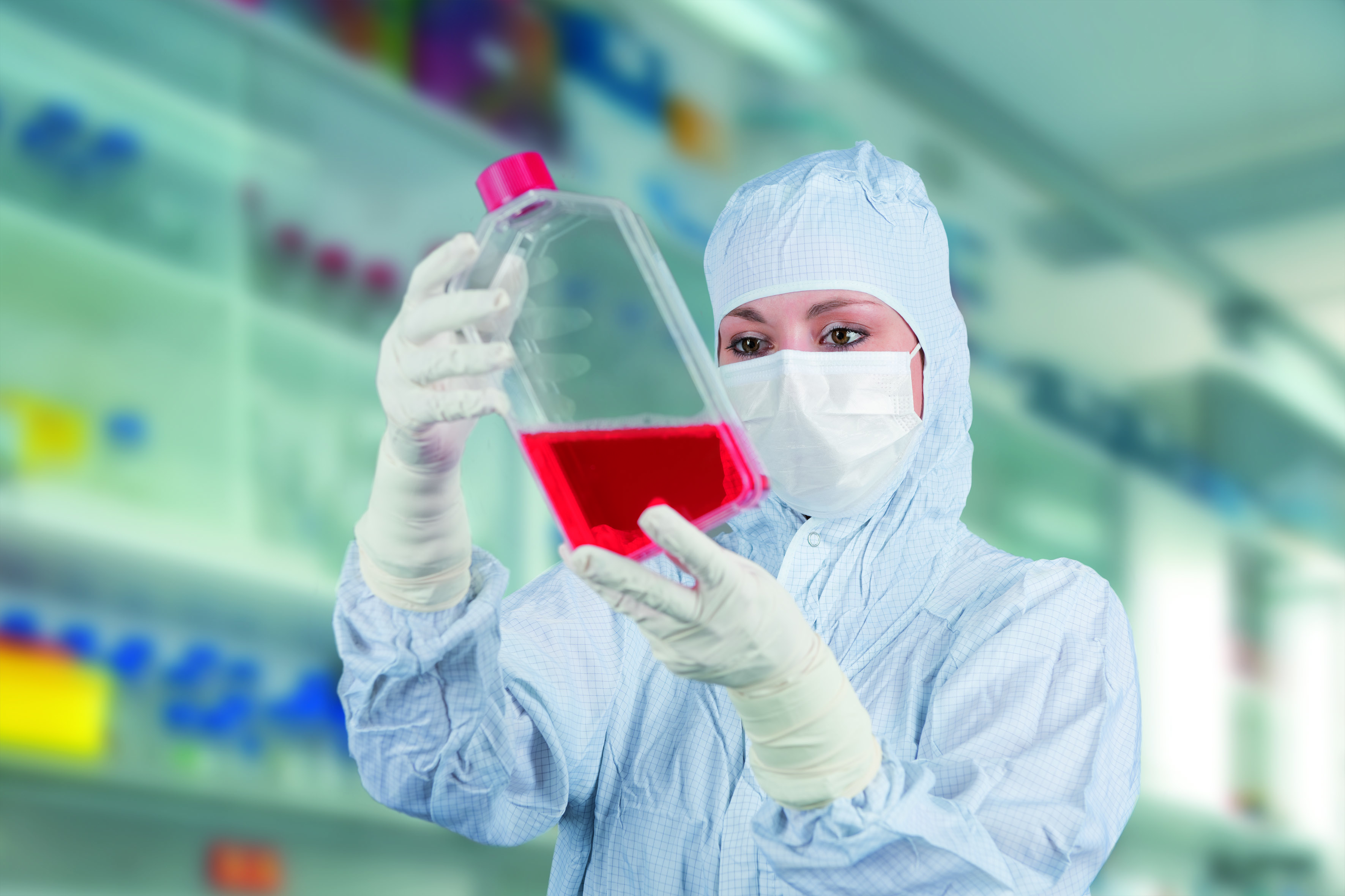 Wissenschaftlerin in Schutzkleidung untersucht eine Flüssigkeit