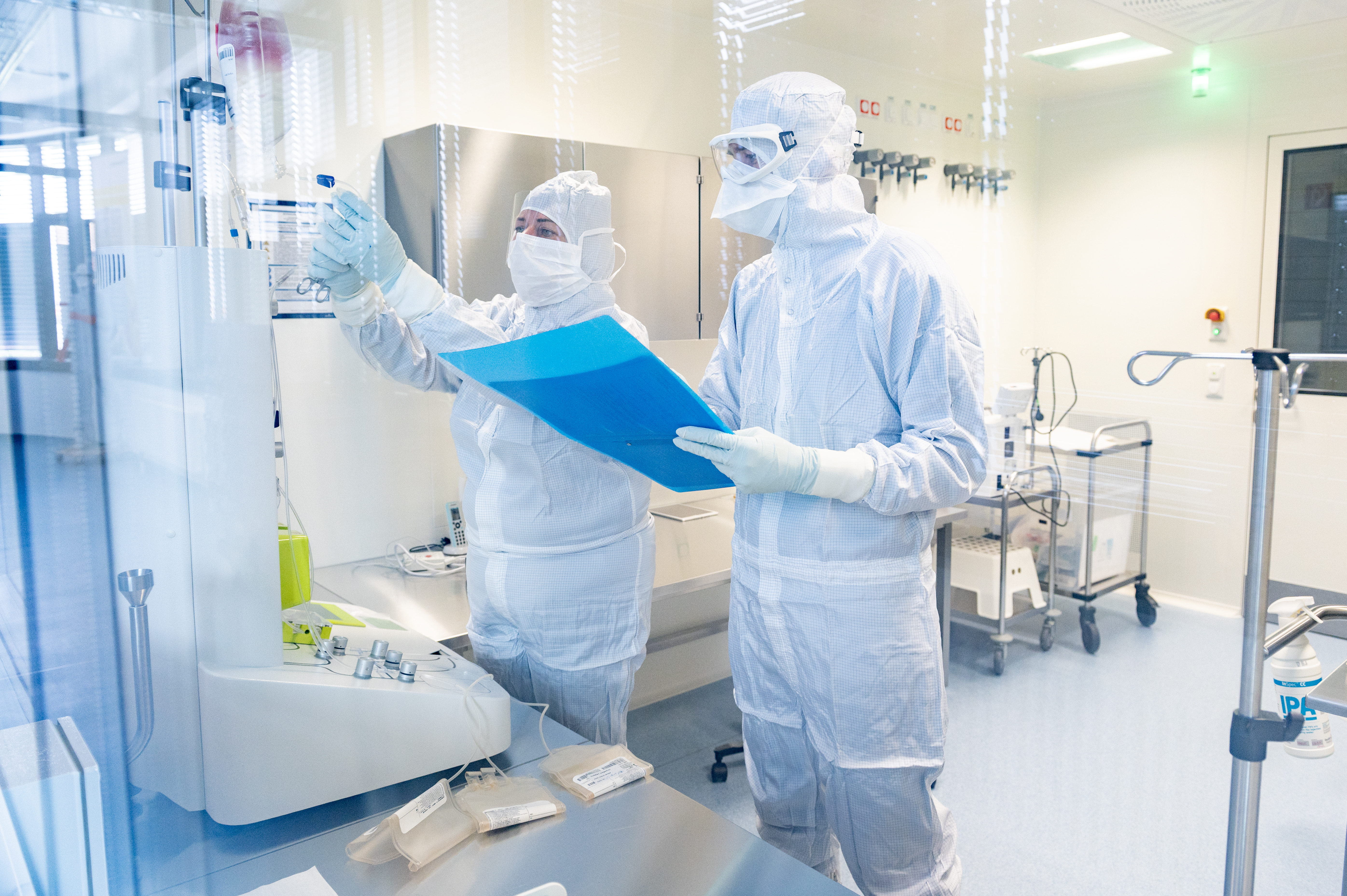 The clinical investigational medicinal products for the LION-1 study are manufactured in the clean room at the Fraunhofer IZI in Leipzig under GMP standards. Two people in protective suits work in the cleanroom.